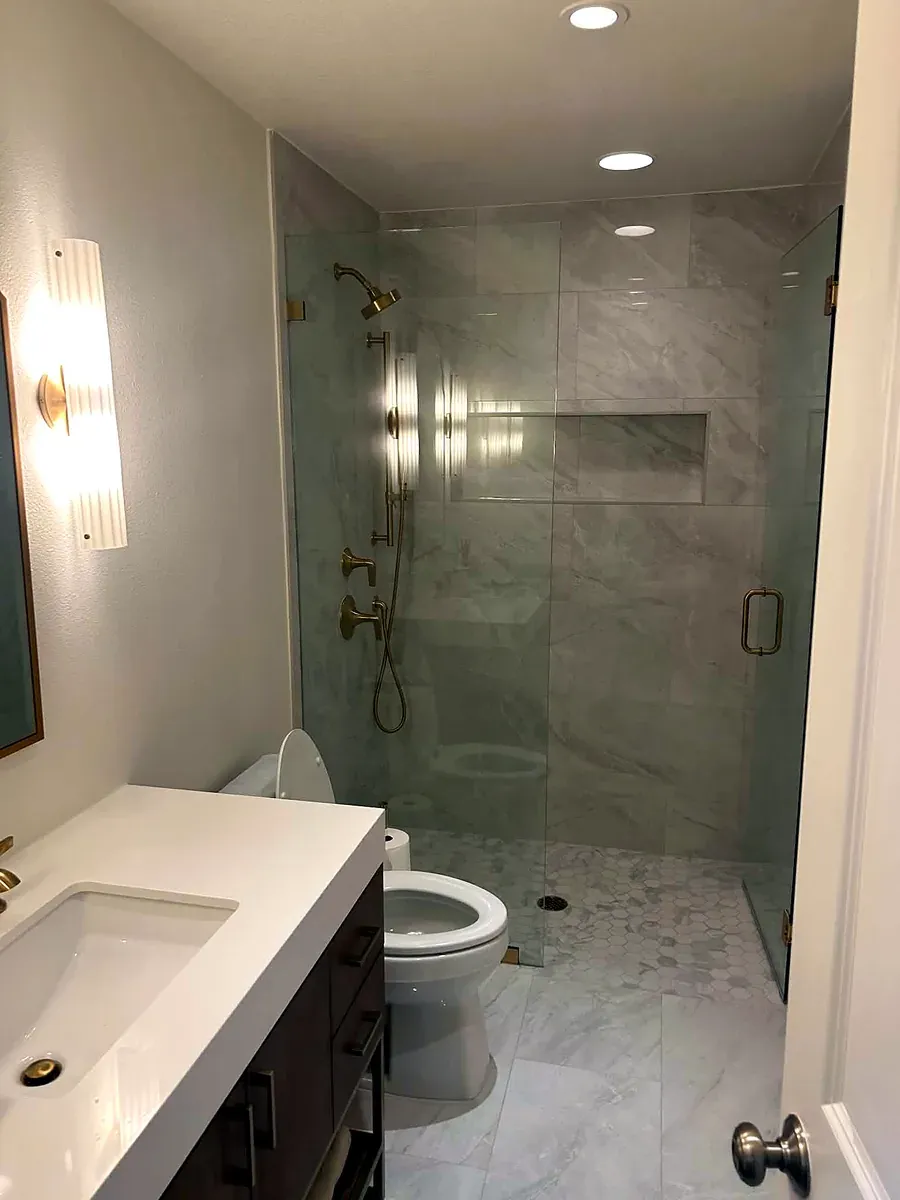 Guest bathroom with a glass walk in shower, marble tile and a white vanity