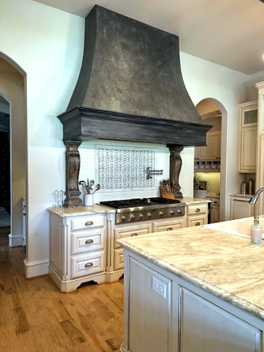 Kitchen with a large plaster range hood on carved corbels over a decorative tile backsplash