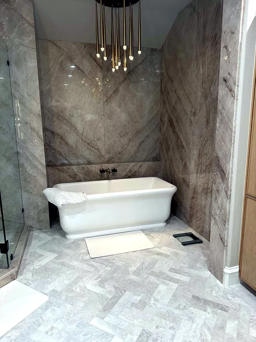 Freestanding soaking tub in a bookmatched marble alcove